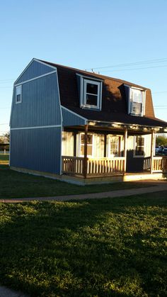 a small house with a porch and covered deck on the grass in front of it