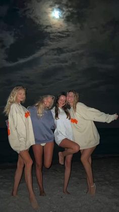 three women are posing on the beach at night