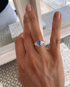 a woman's hand with a ring on it and a blue stone in the middle