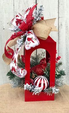 a small red house decorated with christmas decorations and ornaments on top of a wooden table