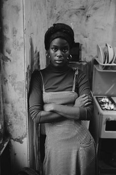 a black and white photo of a woman in an old kitchen