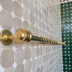 a gold handle on a white and green tiled wall