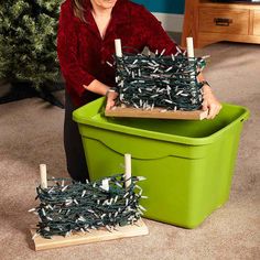 a woman kneeling on the floor next to a green container with candles in it and another box that has sticks sticking out of it