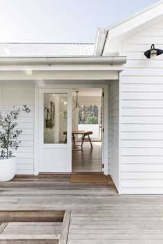 a white house with an open door and potted plant on the front porch area