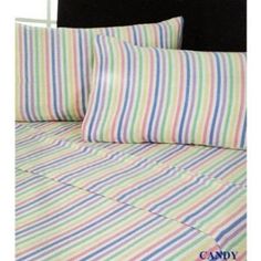 a bed with multi colored striped sheets and pillow cases on it's headboard