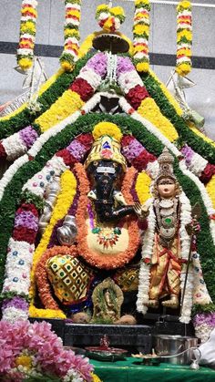 a statue of lord ganesh in front of some flowers and garlands on display