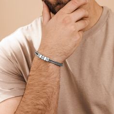 a man wearing a silver bracelet with an arrow design on it's wrist and looking at the camera