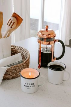 two coffee mugs sitting on top of a table next to a basket with utensils