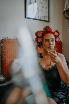 a woman with red hair sitting on a couch holding a martini glass in her hand