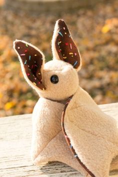 a small stuffed animal with sprinkles on it's ears sitting on a wooden surface