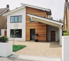 a modern house with wood siding and white fenced in area next to the driveway