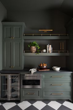 a kitchen with black and white checkered flooring, green cabinets and gold handles