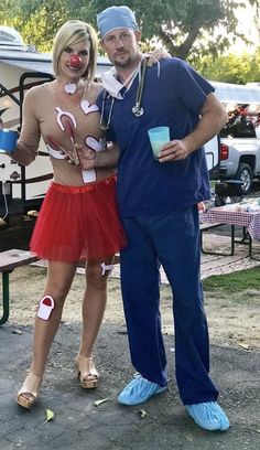 a man and woman dressed up as clowns pose for a photo in front of a tent