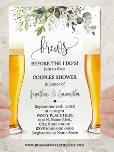 two people holding up beer glasses in front of a wedding shower sign with greenery on it