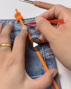 someone is crocheting an orange piece of fabric with scissors and pencils in their hands