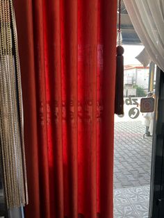 a red curtain is open in front of a window with beads hanging from it's side