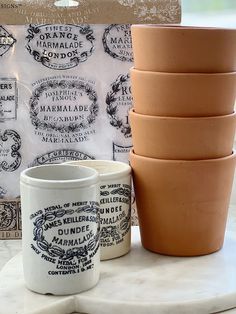 a stack of four ceramic cups sitting on top of a white table next to a box