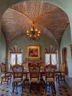 a dining room with a painting on the wall and chairs in front of an arched ceiling