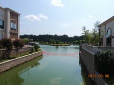 a body of water next to two buildings and trees in front of the building on the other side