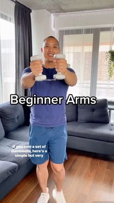 a man standing in front of a blue couch holding two white remotes with the caption beginner arms