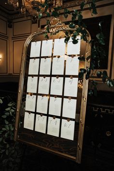 a gold framed mirror with seating cards on it