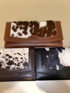 two brown and white cowhide purses sitting next to each other