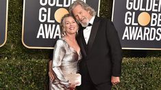 an older man and woman in formal wear posing together on the red carpet at awards