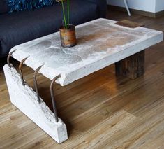 a concrete table with a potted plant on it and a black couch in the background