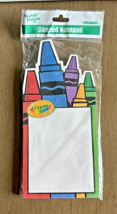 a package of colored crayons sitting on top of a wooden table