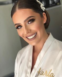 a woman in a white robe with a tiara on her head smiling at the camera