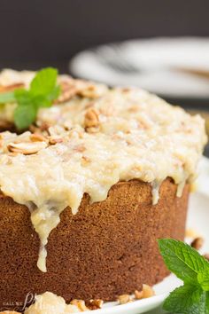 a close up of a cake on a plate with mint garnish and nuts