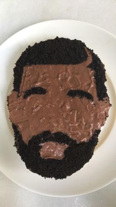 a white plate topped with a cake covered in chocolate frosting and a man's face