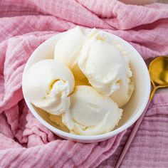 three scoops of ice cream in a white bowl on a pink towel next to a spoon