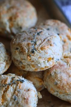 several biscuits with herbs on them sitting on a cutting board next to a fork and knife