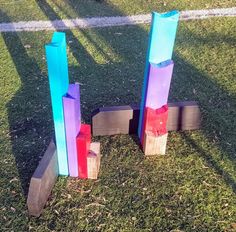 three wooden blocks with colored paint on them sitting in the grass