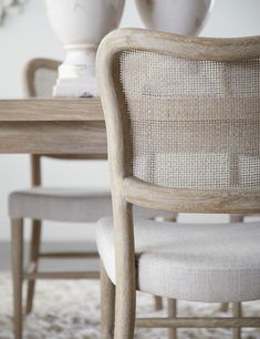 a dining room table with two chairs and a vase