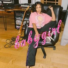 a woman sitting on top of a black chair in front of a recording equipment set