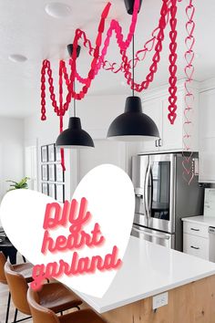 an image of a kitchen decorated for valentine's day with pink hearts hanging from the ceiling