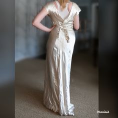 "Pictures don't do this sweetheart justice! 1930's Ivory-colored liquid satin biased cut gown with a plunging back. There is a detail on the butt that makes the skirt more full! High neckline and built in belt to tie the waist. Includes the tag \"A Registered Original Design with Fashion Originators Guild\" Has two discolored spots on the front of the skirt, but I haven't tried any extraordinary washing methods measurements: bust: 36\" waist: up to 30\" hips:max 40\" shoulder to waist: 15\" wais Cream Satin Fitted Evening Dress, Fitted Cream Satin Evening Dress, Fitted Bias Cut V-neck Gown, Fitted Cream Satin Maxi Dress, Vintage V-neck Evening Dress, Vintage Satin Evening Gown, Vintage Satin Gown For Evening, Fitted Silk Gown For Vintage Events, Fitted Cream Bias Cut Gown