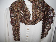 a woman wearing a white shirt and a brown scarf with multicolored crochet on it