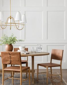 a dining room table with two chairs and a potted plant