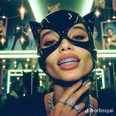 a woman wearing a black cat mask and diamond ring with her hands on her chest