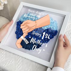 two hands are holding a blue rosette bouquet with the words happy mother's day written on it