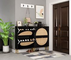 a living room with a black cabinet and potted plant in front of the door