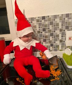 a child dressed as an elf sitting on top of a stove