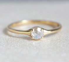 a gold ring with a white diamond in the center on a table top, ready to be used as an engagement or wedding ring