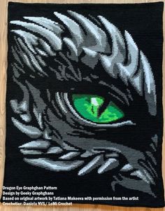 a close up of a green eye on a black cloth with white and grey designs