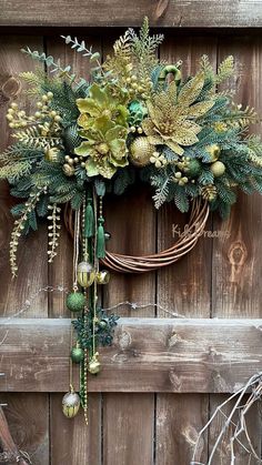 a wreath is hanging on the side of a wooden door with flowers and greenery