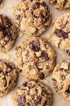 chocolate chip cookies are arranged on a piece of parchment paper with crumbled edges