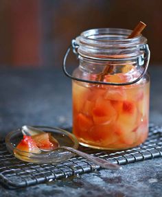 a glass jar filled with pickled fruit on top of a metal grate next to a spoon